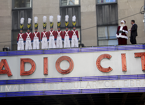 As Santa and radio host John Foxx look on, the famed Radio City Rockettes perform the Parade of the Wooden Soldiers on the theater&#39;s marquee.