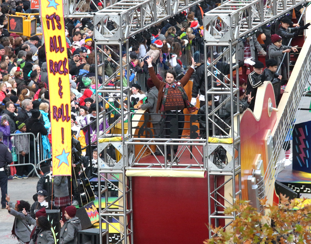 Alex Brightman (center) and the cast of Broadway&#39;s School of Rock head down the Macy&#39;s Thanksgiving Day Parade route on the Gibson Guitars float.