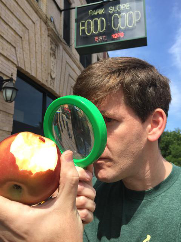 Murder at the Food Coop composer Marc Dinkin inspects an organic, non-GMO, free-range apple in Park Slope.