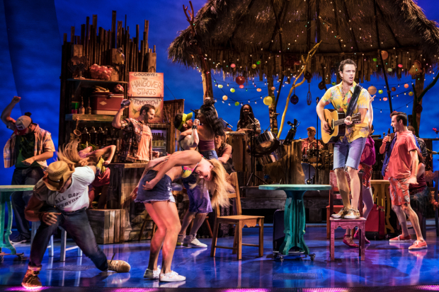 Paul Alexander Nolan (on chair) leads the cast of Escape to Margaritaville in a rousing moment from the show.