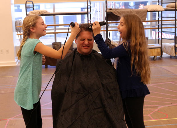 Christopher Sieber (center) gets a haircut from Cassidy Pry and Peyton Ella for his role as Oliver Warbucks in Annie, directed by Mark S. Hoebee, at Paper Mill Playhouse.