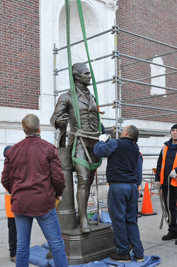 The statue of Alexander Hamilton is made ready to be lifted back into place.