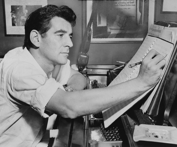 A young Leonard Bernstein annotates a score at the piano.