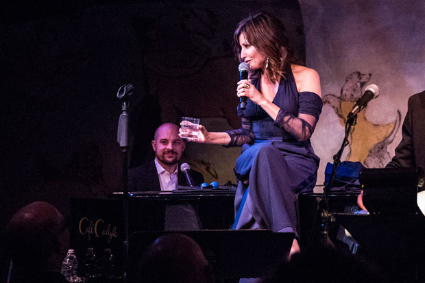 Gina Gershon sits on the piano with Eli Brueggeman at the keys at the Café Carlyle.