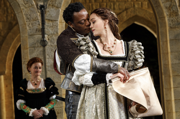 Emilia (Alison Wright) looks in as Othello (Chukwudi Iwuji) embraces Desdemona (Heather Lind) in Othello.