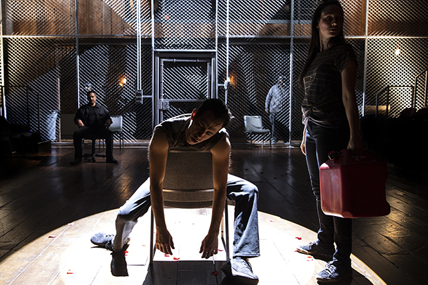 Arturo Ui (Raúl Esparza, background) looks on as a witness of the warehouse fire (George Abud) slumps over next to Giri (Elizabeth A. Davis) in The Resistible Rise of Arturo Ui.