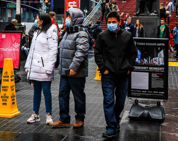 Masked visitors take a stroll around New York&#39;s Times Square. 