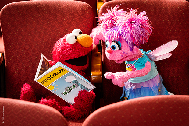 Elmo and Abby Cadabby peruse the show program at Sesame Street the Musical.