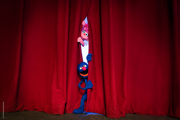 Abby Cadabby and Grover peek through the curtain at Sesame Street the Musical.