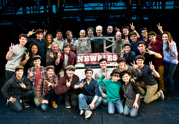 The current Broadway cast of Newsies poses with its specially designed cake from City Bakery.