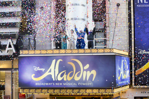 The cast of Aladdin partakes in the annual confetti test with Times Square Alliance President Tim Tompkins over the marquee of the New Amsterdam Theatre.