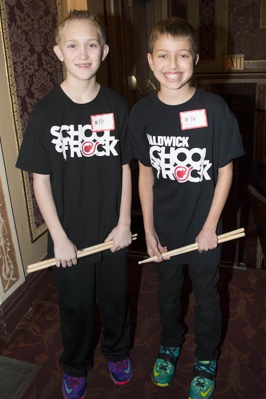 A pair of young musicians proudly show off their drum sticks.