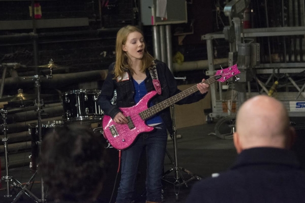 A pink electric guitar helps this young actress get into the spirit of the show.